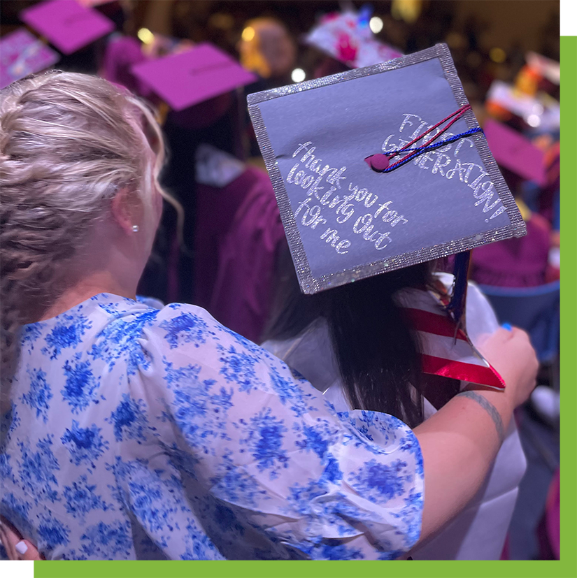 Graduation photo of teacher with arm around student wearing cap hand-decorated with the message: "First Generation: Thank you for looking out for me"